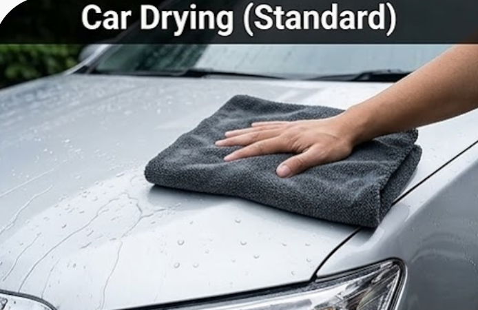 Absorbent microfiber towel drying water droplets on standard car paint surface